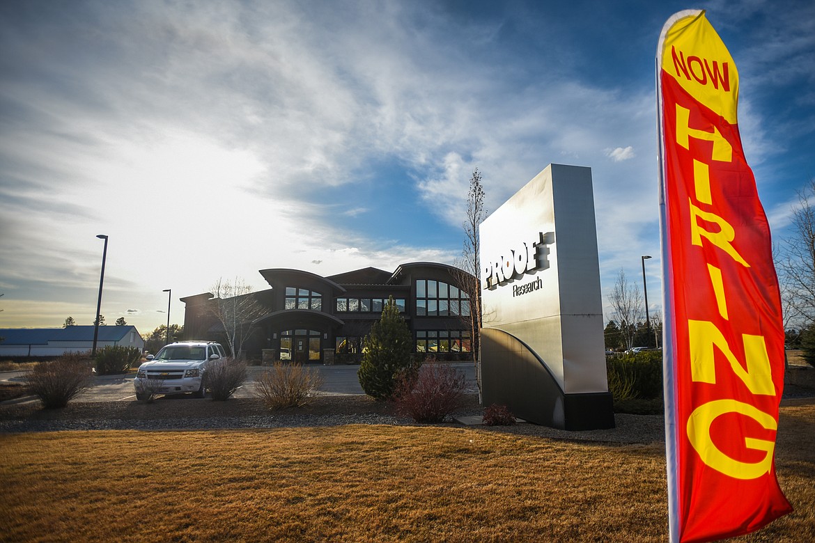 A "Now Hiring" sign waves in the wind in front of Proof Research along U.S. 2 on Thursday, March 18. (Casey Kreider/Daily Inter Lake)