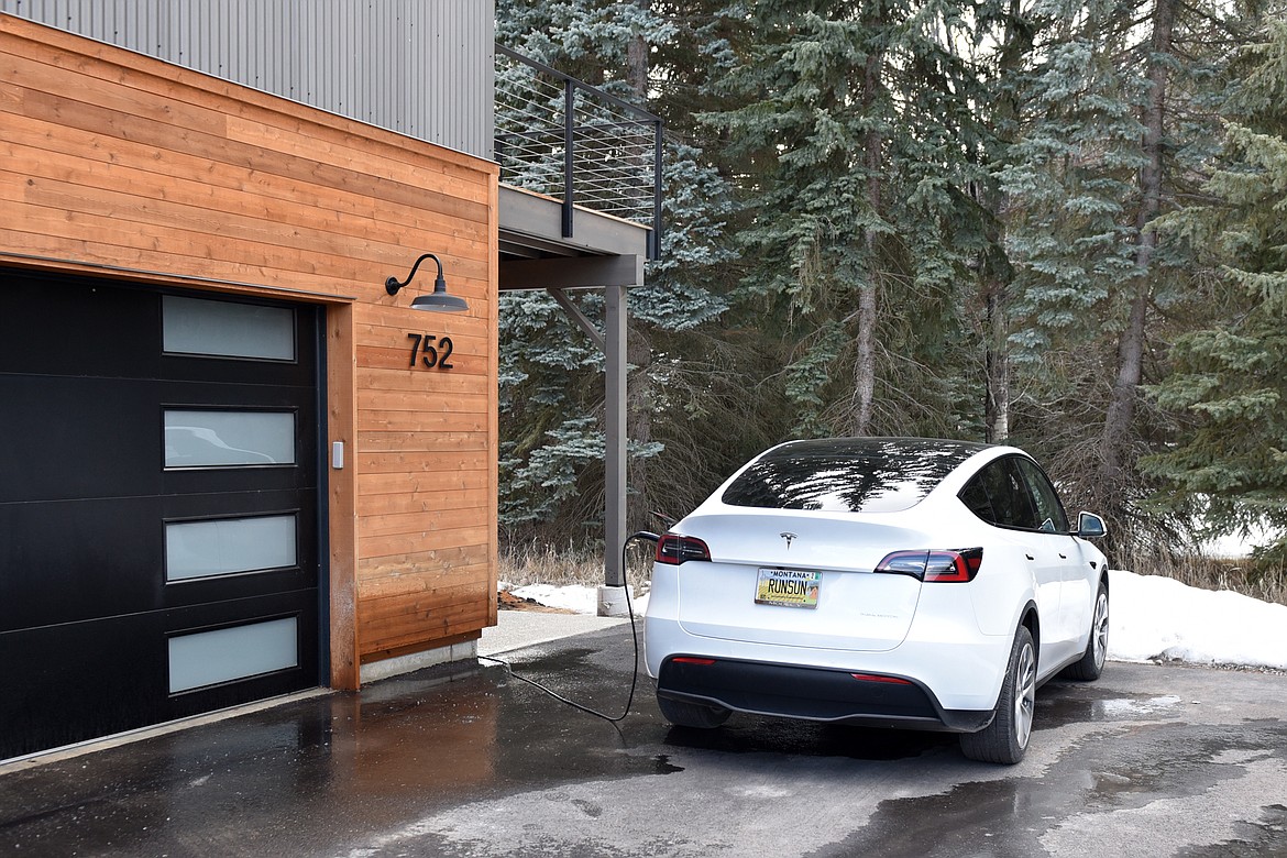 Lee Calhoun charges his electric car outside his home on Salmon Run. He expects the solar panels on the roof of his home to generate enough electricity for both his home and to charge his car. (Heidi Desch/Whitefish Pilot)