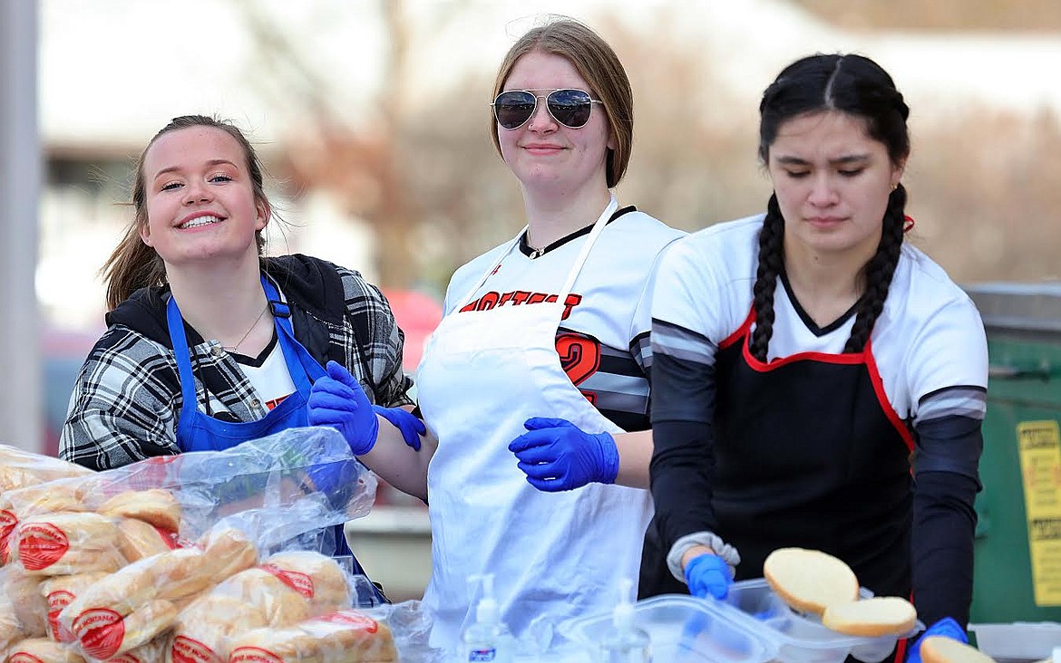 Plains Trotters softball players, from left, Gena Dechamp, Izibella Crabb and Jolina Caldwell have fun while preparing food to go for team fundraiser Saturday at the high school. (Photo courtesy Jessica Peterson)