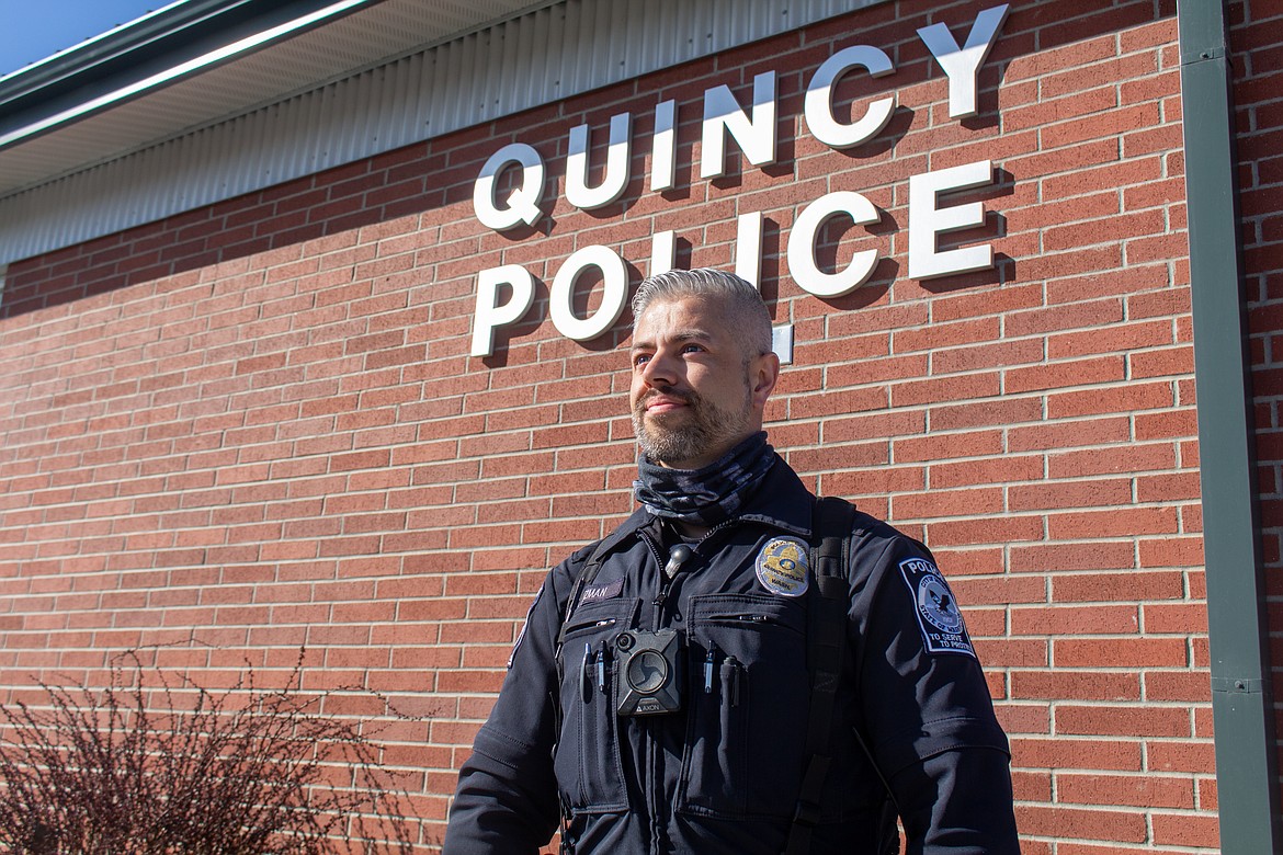 Quincy police officer Abraham Guzman stands outside the Quincy Police Department at the corner of First Avenue Southwest and C Street Southwest in Quincy on Tuesday afternoon.
