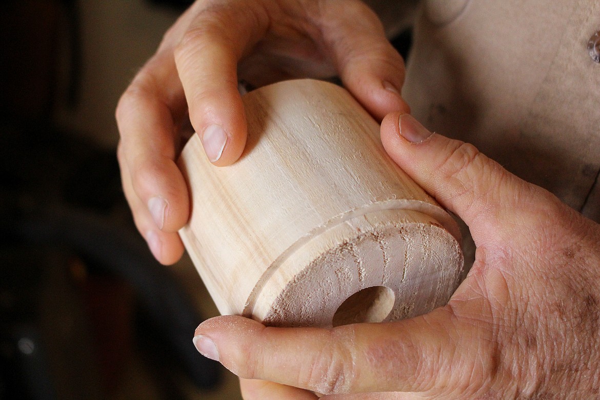 Merle Hardy runs his fingers across an unfinished wood ornament out in his "woodturning shop" in his garage in Moses Lake on Monday.