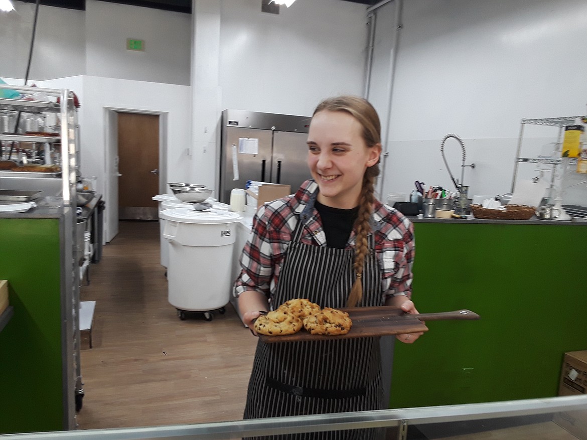 Izzy Epps, baker at the Bear Paw Cookies in Riverstone, pulls out a tray of the bakery's famous chocolate chip cookies for a customer Monday. While the aroma is delightful enough to lure in passers-by, Epps said the scent of freshly-baked cookies can only travel so far. "Foot traffic is a big thing," she said. "That's normally how people find us." CRAIG NORTHRUP/Press)