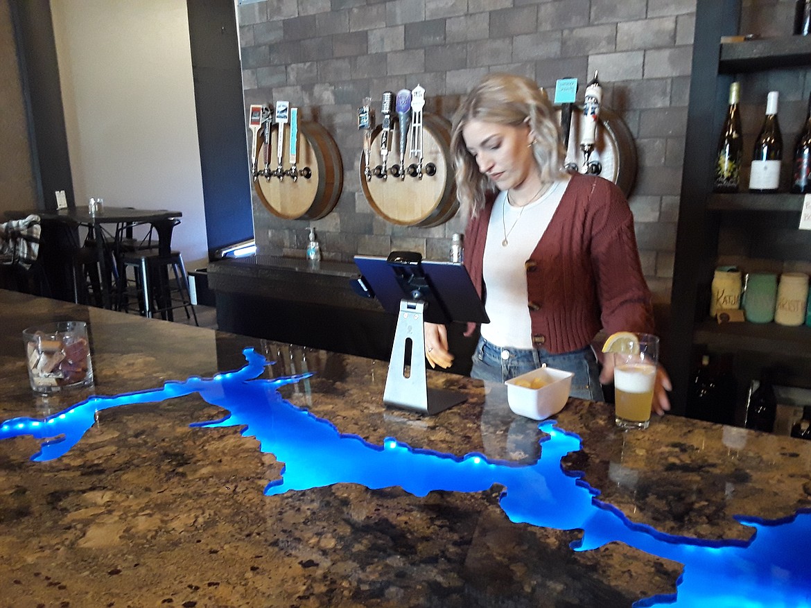Katja Bartsch minds the till at the Cork & Tap Monday afternoon. The general manager of the popular Riverstone wine bar said her fellow Riverstone businesses have been suffering from the foot traffic the nearby Regal theater once provided. (CRAIG NORTHRUP/Press)