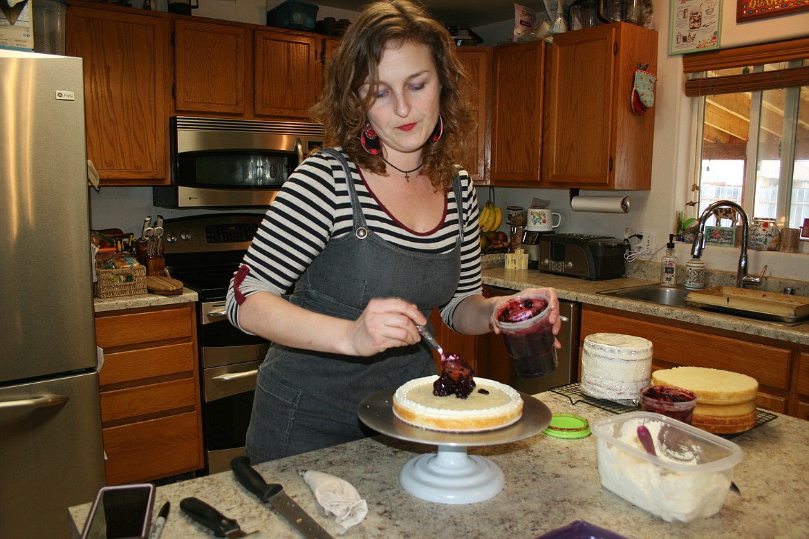 Shawna Sloane,owner of Risen Indeed Cakes and Pastries, adds homemade blackberry filling to a layered cake.