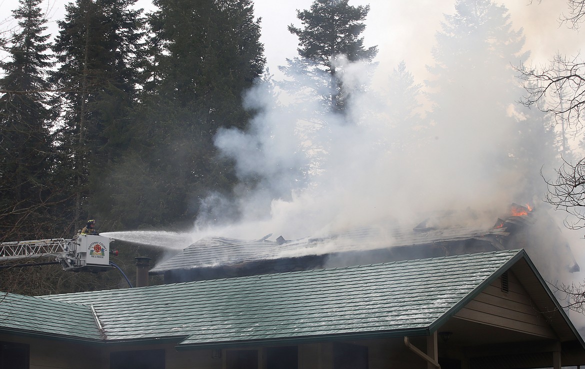 Firefighters spray water on a home on fire on East Fernan Lake Road Thursday.