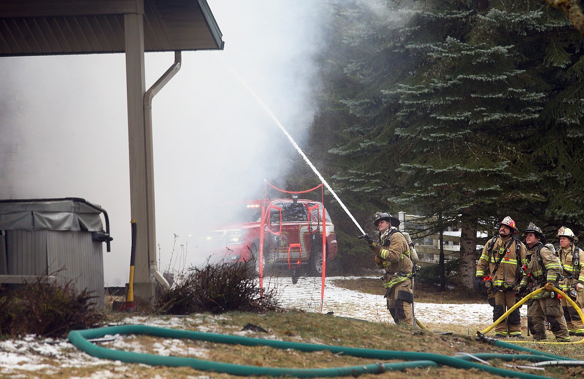 Firefighters steady a hose as they battle a fire on East Fernan Lake Road Thursday.