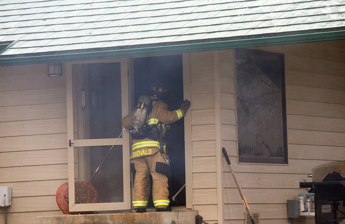 Firefighter Bob Shovald inspects the inside the guest home next to the main home that caught fire Thursday on East Fernan Lake Road.