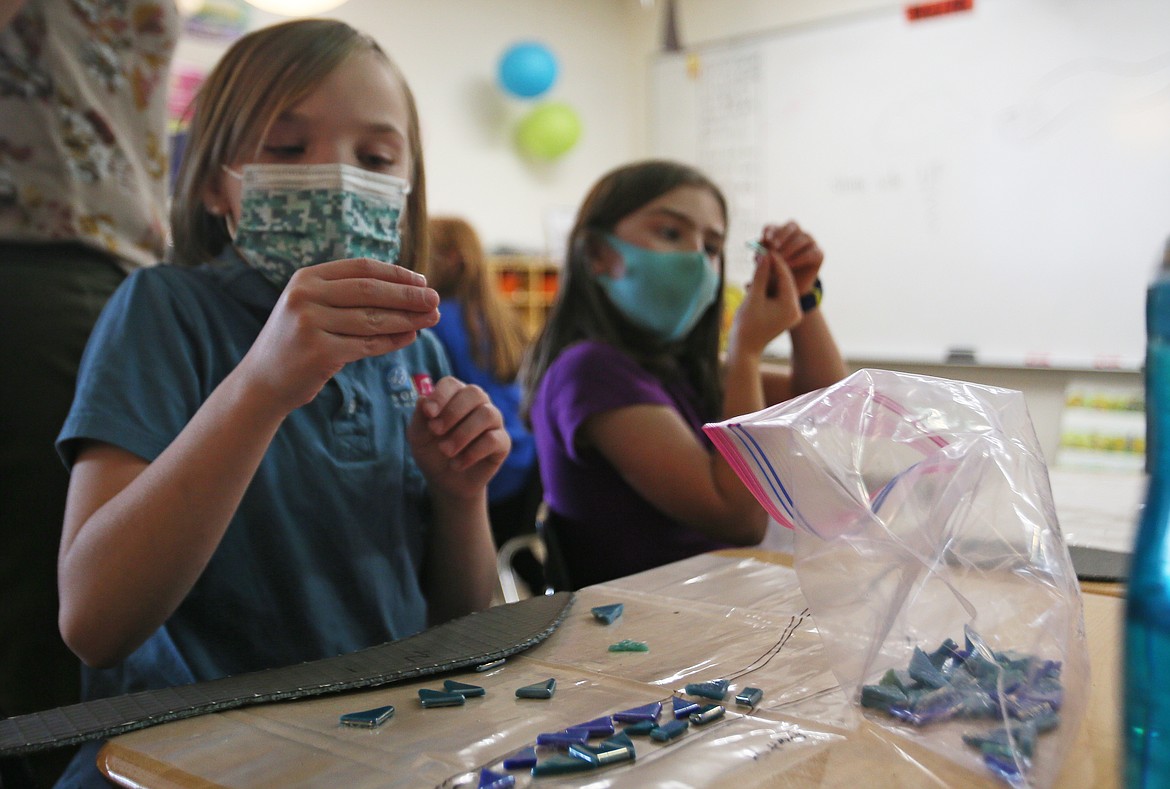 Third-graders Bella Swingrover, left, and Tia Frank carefully decide which pieces go where while working on mosaic art Thursday afternoon. All grades at Sorensen Magnet School are contributing to a mosaic and painted mural with the help of artist-in-residence Melissa Cole.