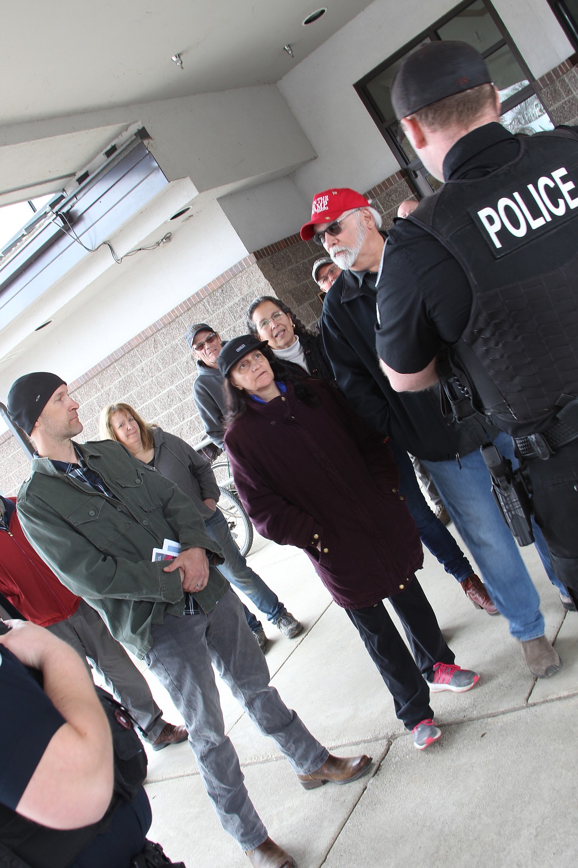 Officer Jeremy Inman talks with Jalon Peters (left) and Angelo Lonzisero (right) during Saturday's mask protest at the Sandpoint Library. (Photo by KEITH KINNAIRD)