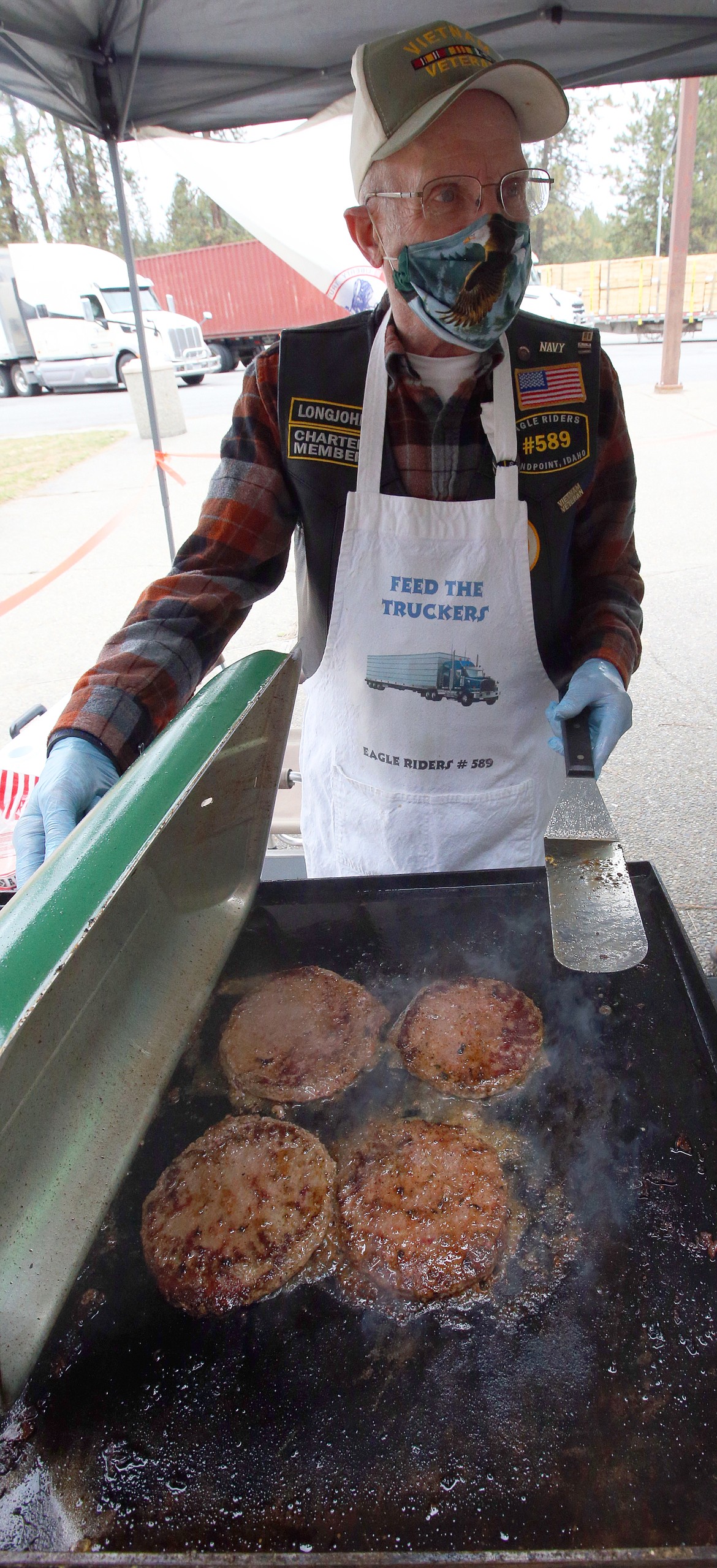John Loomer Sr. with the Eagle Riders cooks up burgers for truckers at the Huetter rest stop.