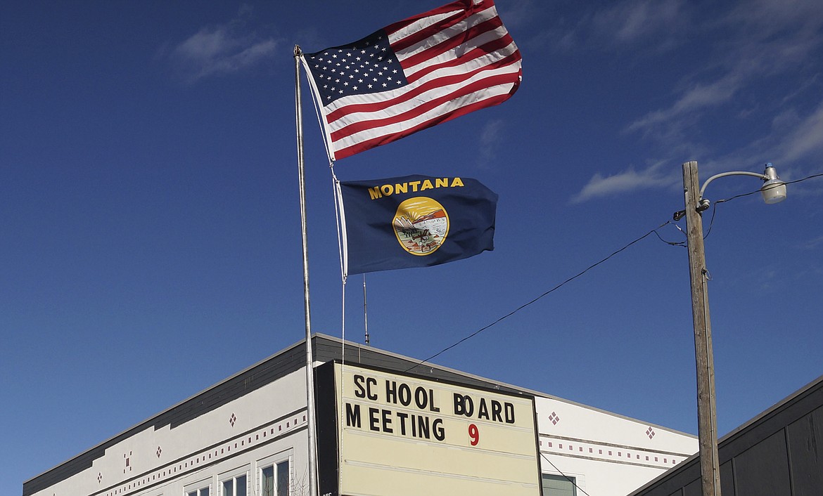 In this Jan. 28, 2015, file photo, an American flag and a Montana state flag fly in front of Harrison High School, in Harrison, Mont. A proposal to change the Montana state flag to prominently feature firearms failed Friday, March 26, 2021, to pass a vote by the state House, after a Republican lawmaker said such a change would honor the state's history. "Who doesn't want to have a great gun flag?" Republican Rep. Caleb Hinkle asked during a hearing on his proposal. (AP Photo/Alison Noon, File)
