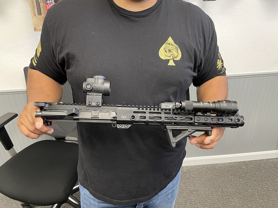 Edgar Salazar holds an AR-15 upper receiver he custom created himself.