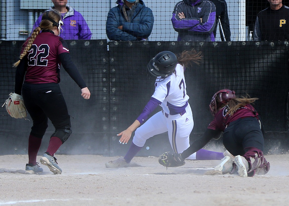 Josie Caye slides around the catcher to avoid the tag and score a run against Butte Central. (Courtesy of Bob Gunderson)