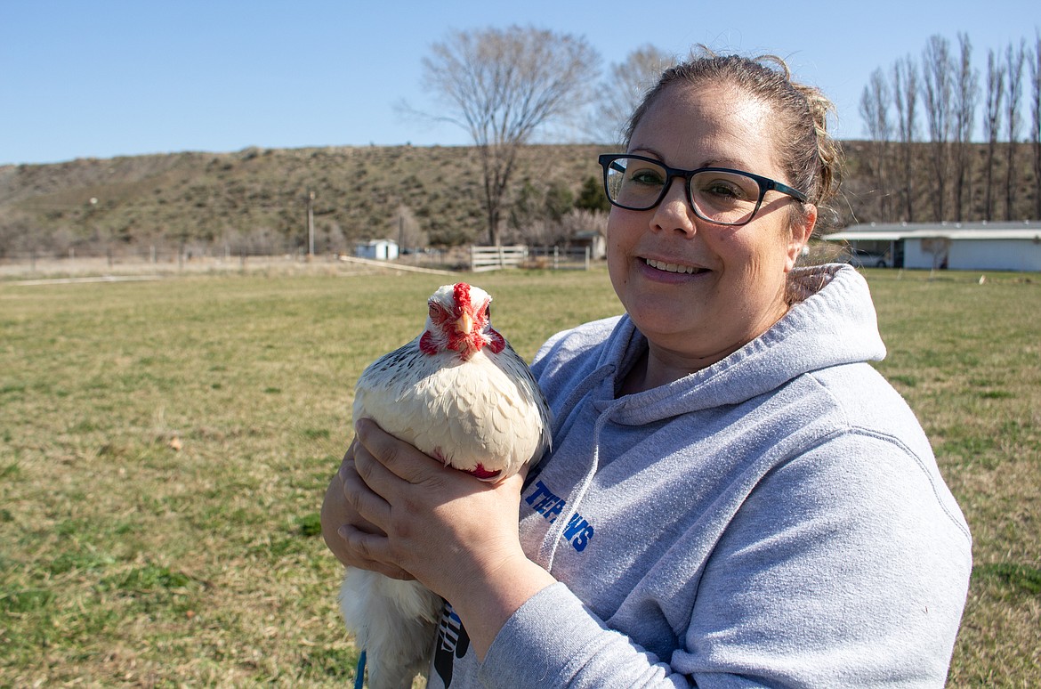 Jesyka Morrison holds up one of her chickens outside an in-law's home where the animals are staying while the family's new home is being built.