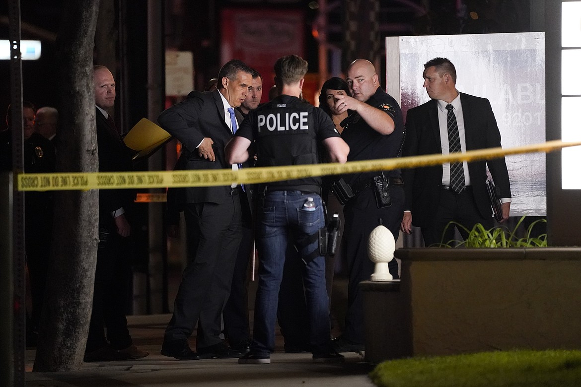 Investigators gather outside an office building where a shooting occurred in Orange, Calif., Wednesday, March 31, 2021. The shooting killed several people, including a child, and injured another person before police shot and wounded the suspect, police said.