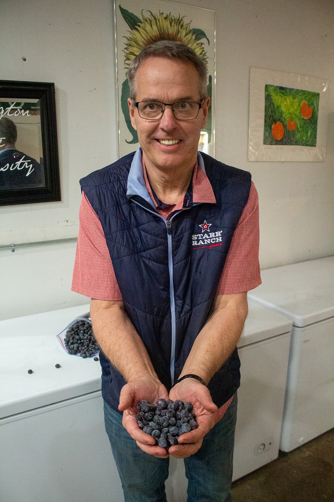 Stacey Sarty of Moses Lake holds a handful of blueberries inside his shop beside his home outside of Quincy on Wednesday afternoon.