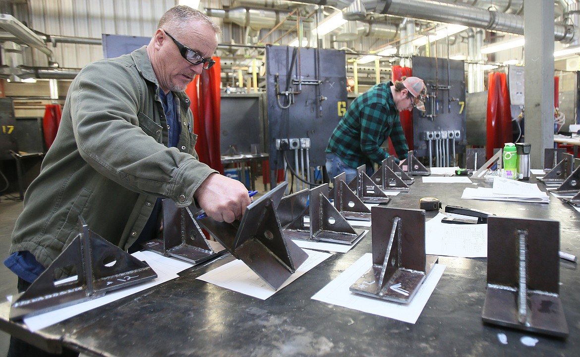 North Idaho College welding instructor Tim Straw inspects and critiques the finished products Friday during a welding competition at KTEC.