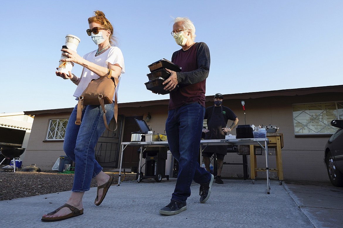 Customers take home dinner after watching chef Mike Winneker prepare it in front of his home Saturday, April 3, 2021, in Scottsdale, Ariz., on April 3, 2021. (AP Photo/ROSS D. FRANKLIN)