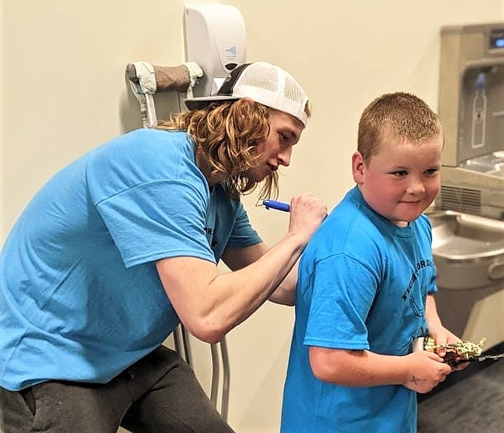 Isaiah Allik, already a local celebrity for his undefeated wrestling season and state championship last year, signed shirts (here, for William Sharbono) at the benefit wrestling meet held last weekend to help cover his cancer treatment expenses. (Courtesy of Daisy Adams)