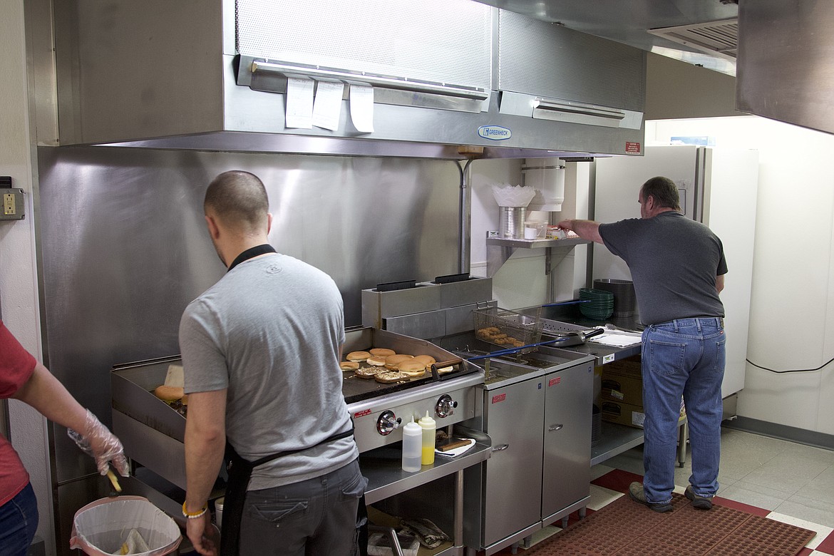 Dale Merkt, right, and his son-in-law Justin Reynolds work the grill at Brad's Burgers on April 6. Merkt and his family opened the eatery in December in memory of his son Brad. (Will Langhorne/The Western News)