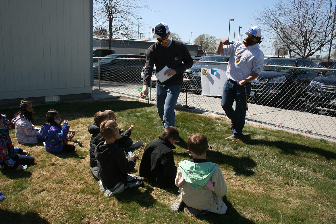 Marshall Tibbs (standing, left), Moses Lake High School FFA, hands out the prizes while Austin Kern (standing, right) calls out the winners of a quiz on Washington agricultural products on First Grade Farm Day Wednesday at Peninsula Elementary School.