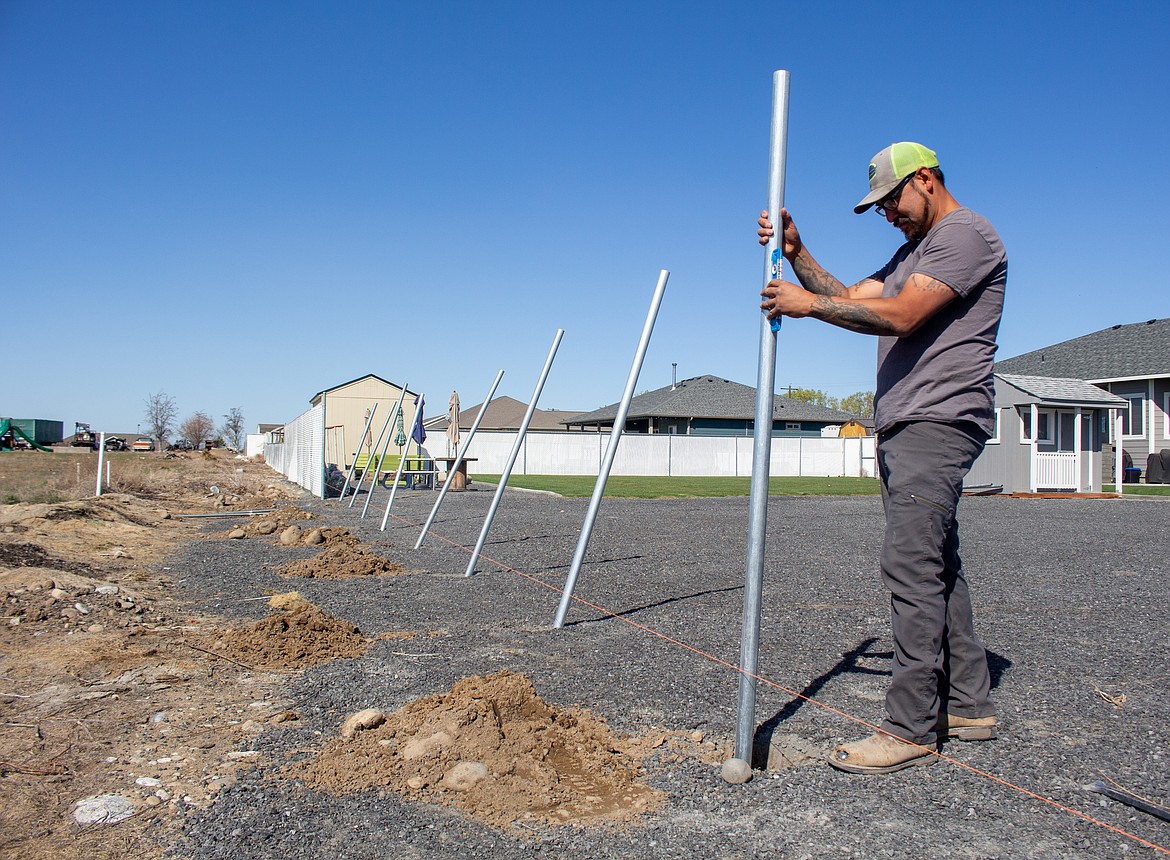 Eddie Ramirez with Cortez Fencing in Moses Lake secures the poles for a chain link fence going up at a home outside of Moses Lake on Thursday morning.