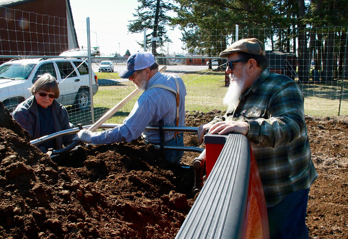 Yvonne and Lowell Nelson distribute manure on the Evergreen Community Garden while Rick Reiss looks on.
Courtesy Dan Hafferman