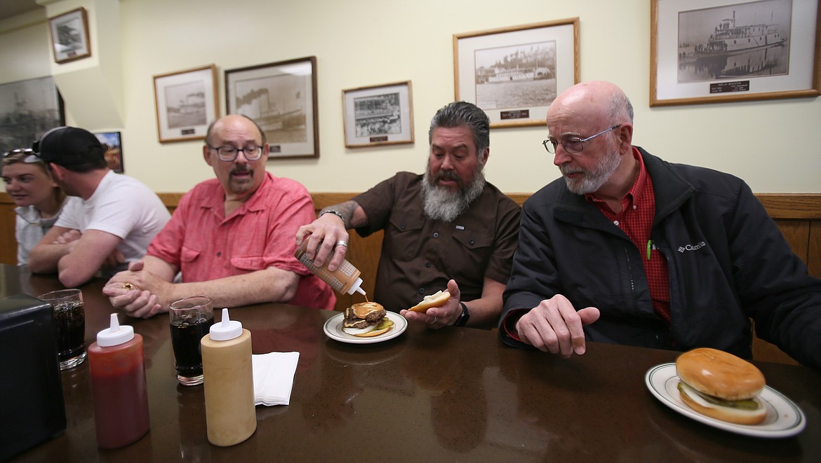 Mike Ward, center, coaches Huddy Burger first-timer Ralph Kerr on proper saucing techniques while enjoying lunch in Hudson's Hamburgers on Friday.