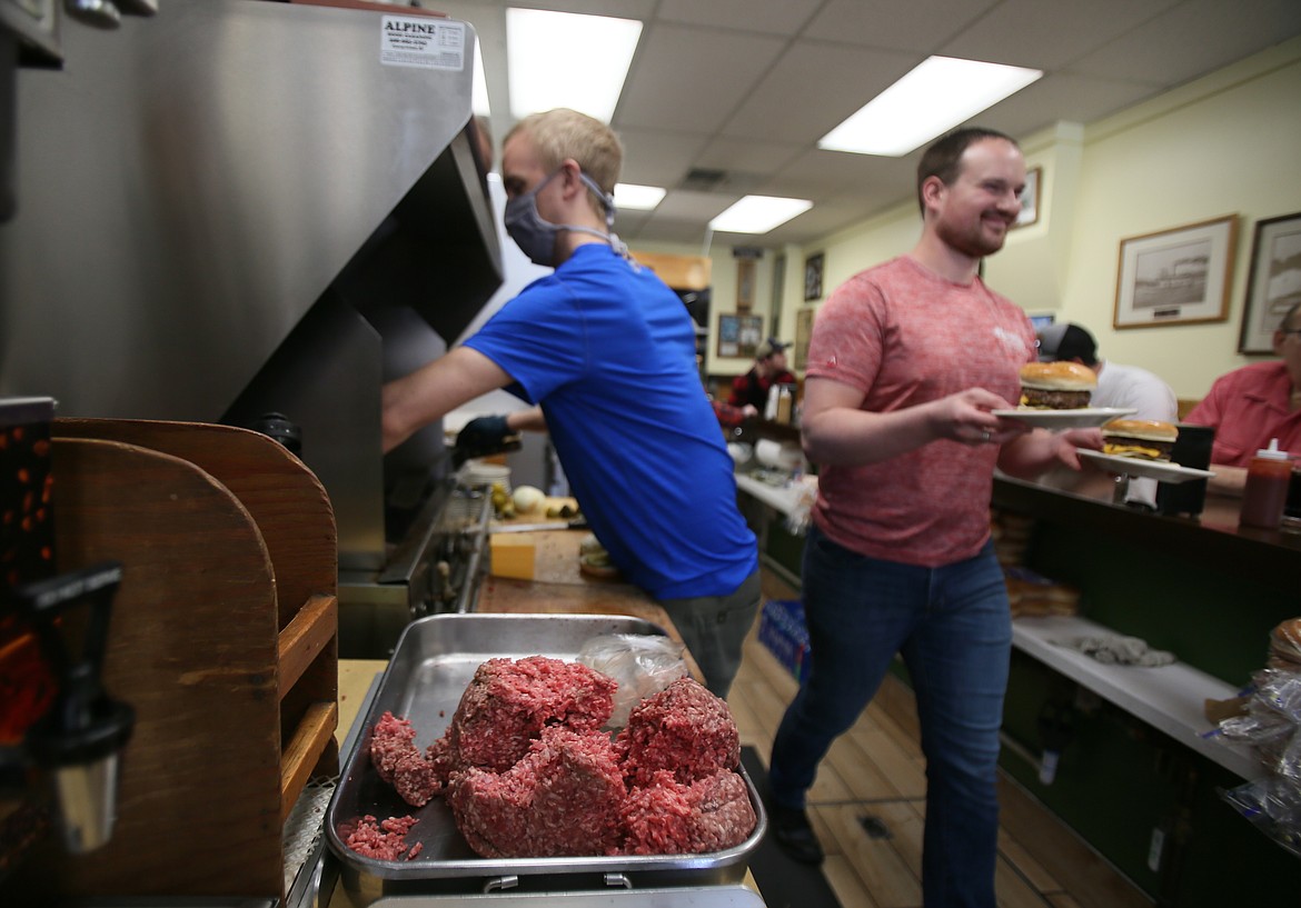 Fresh beef is a key ingredient in the famous Huddy Burger at Hudson's Hamburgers, cooked by Jeremy Babcock, left, and served with a smile by Dawson Williams on Friday.