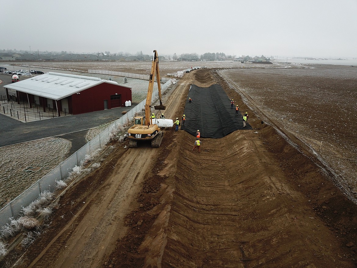 Workers with the Quincy-Columbia Basin Irrigation District install a plastic liner under the W26A tributary canal north of the new Quincy High School campus.