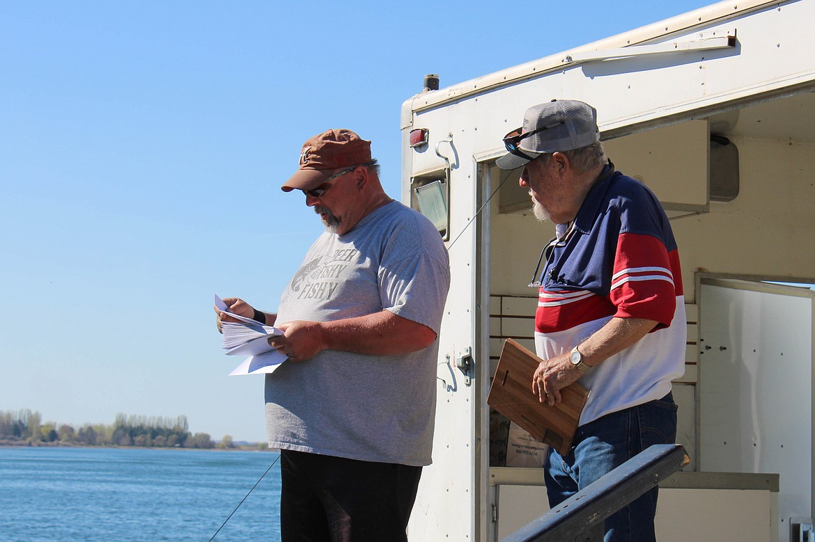 Potholes Bass Club president Paul Harmon (left) and treasurer Merle Armstrong (right) read of winners at the 41st Potholes Open on Sunday.