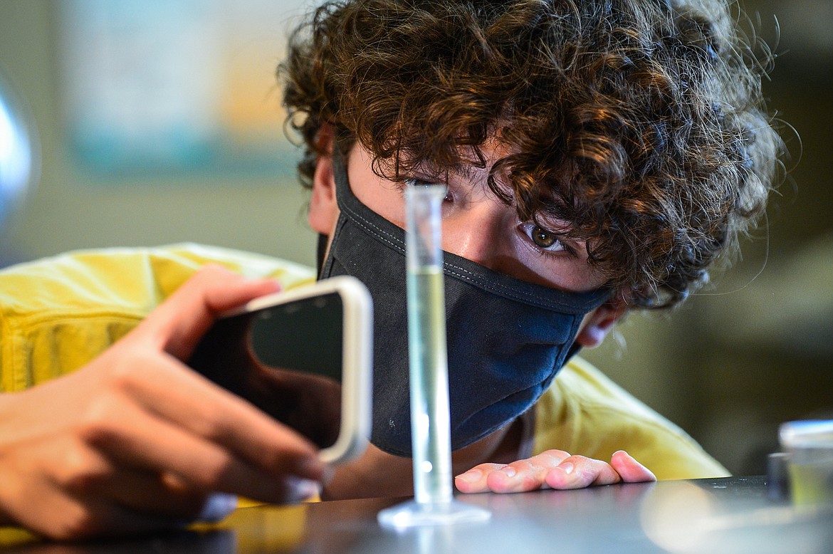 Derek Smith uses the light on his cell phone to check a sample of water containing algae for brine shrimp during David Lillard's AP Biology class at Glacier High School on Wednesday, April 21. (Casey Kreider/Daily Inter Lake)