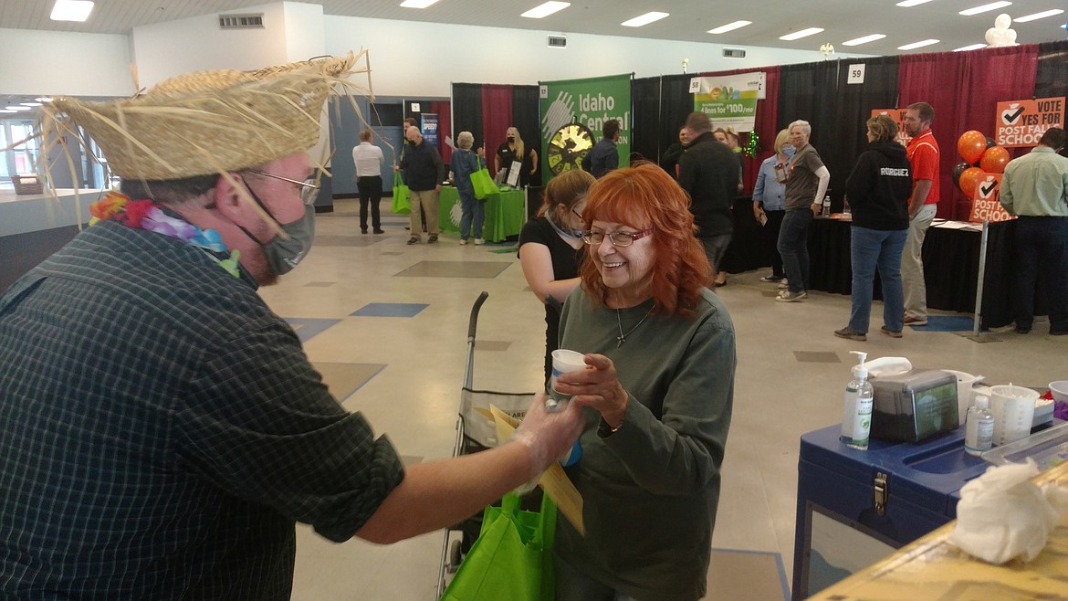 Lorraine La Pietra accepts a tasty Kona Ice treat Wednesday from North Idaho College Workforce Training Center's Tom Greene during the Post Falls Community Business Fair. Greene and his colleagues wore grass hats and skirts to give their booth a proper tropical flair.