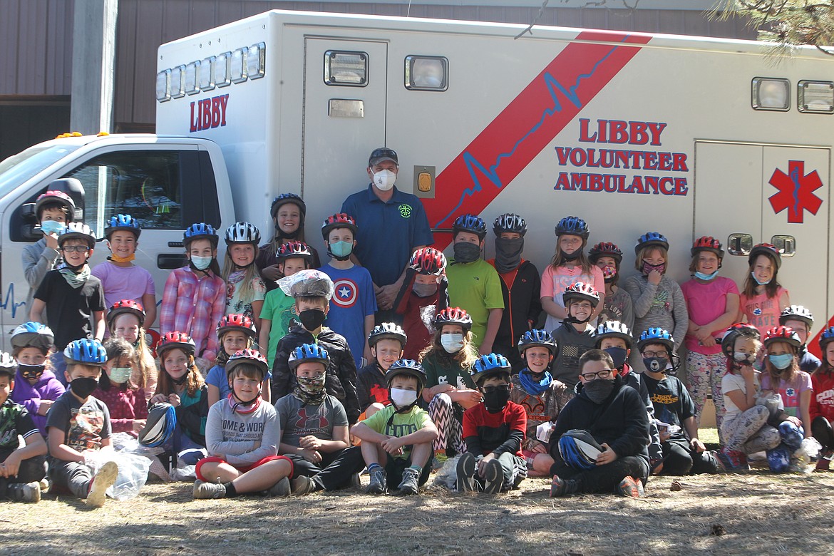 Jeff Holder, of Libby Volunteer Ambulance, poses with third grade students at the Libby Elementary School on April 20. Volunteers showed students around the ambulance and gave out bike helmets. (Will Langhorne/The Western News) d