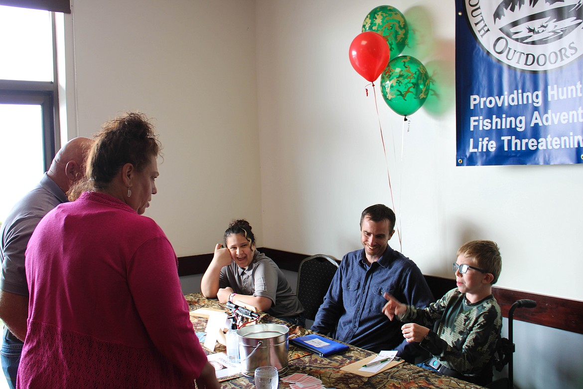 Jared Chartier (center) and his son, Caleb (right), sell 'tear cards,' chances to win the Colt 1911 pistol on the table.