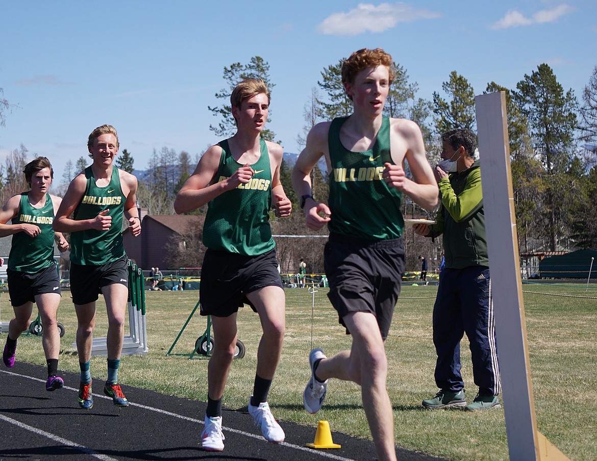 A pack of Bulldogs including Nate Ingelfinger, Landon Brown, Reudi Steiner and William Hyatt   compete in the 3,200 meter run while Head Distance Coach Richard Menicke offers encouragement at Whitefish High School on Tuesday, April 20. (Matt Weller photo)