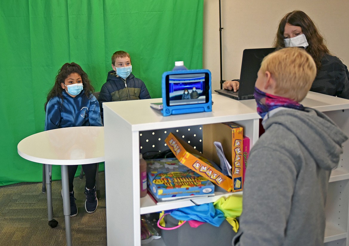 Muldown News anchor Audrey Jones and special reporter Hudson Clark give a report while Kaleb Stevens records them using a tablet and Gianna Mitchell uses a laptop as a teleprompter at the elementary school on Thursday. (Whitney England/Whitefish Pilot)