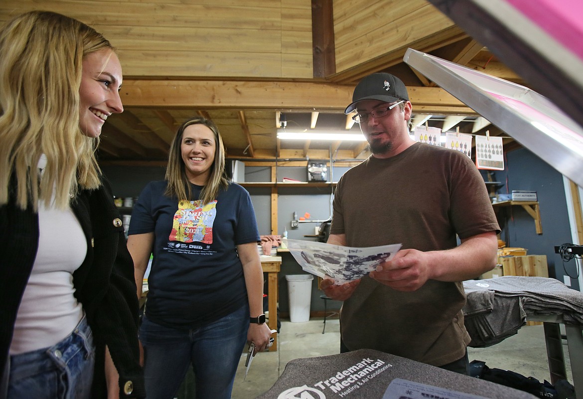 StandOut Promotion screenprinter Dillon Dionne, right, shows Maysen Deming some of the steps to turning her design into a T-shirt during a visit to the shop Monday. Also pictured: United Way of North Idaho resource development manager Brittany Teverbaugh.