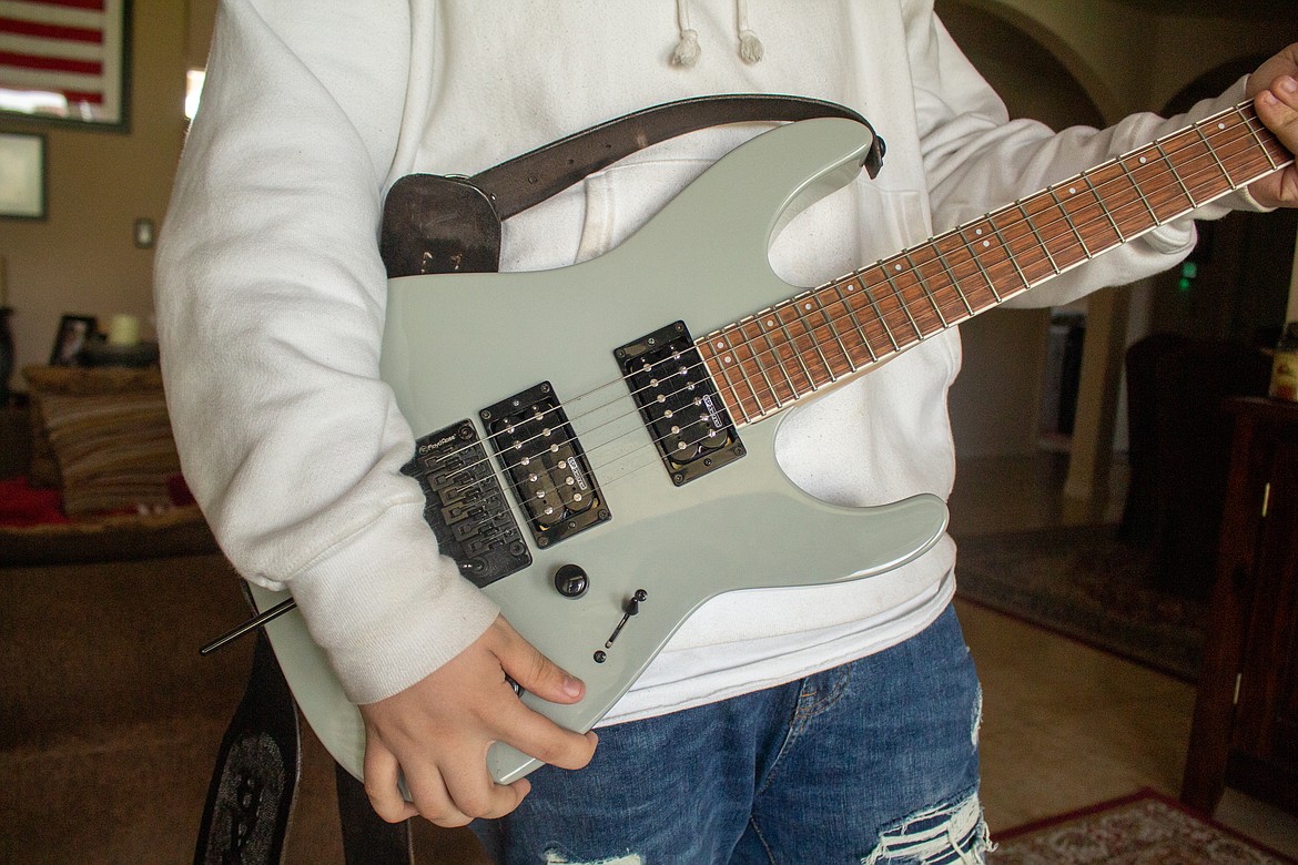Gunnar Rimple of Moses Lake holds his "go-to" guitar, a gray LTD electric guitar with a Floyd Rose bridge inside his family's home in Moses Lake on Tuesday afternoon.