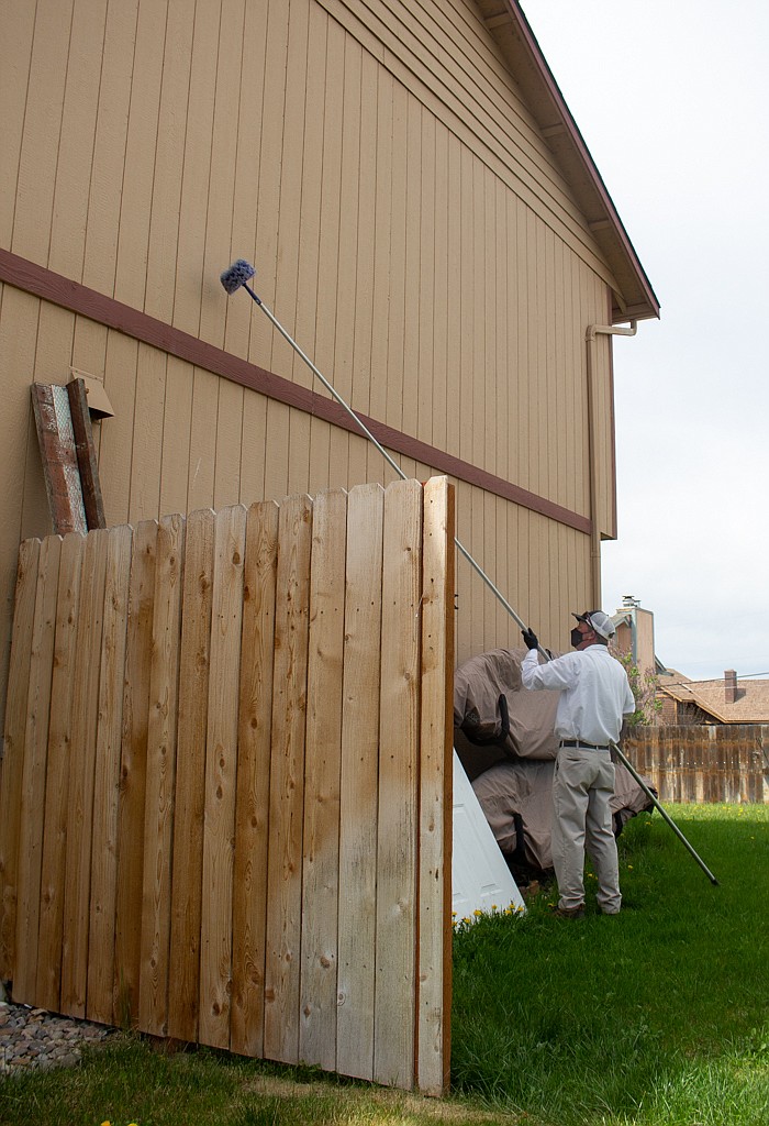 Allan Kooy with Pointe Pest Control pulls in his extendable brush after clearing away some wasps nests and spiderwebs from near the eve of the roof on a home in Moses Lake on Wednesday afternoon.