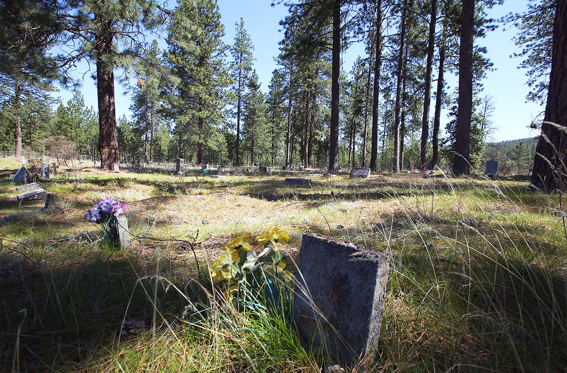 Grass, weeds and flower grow near gravesites at Pleasant View Cemetery in Post Falls.