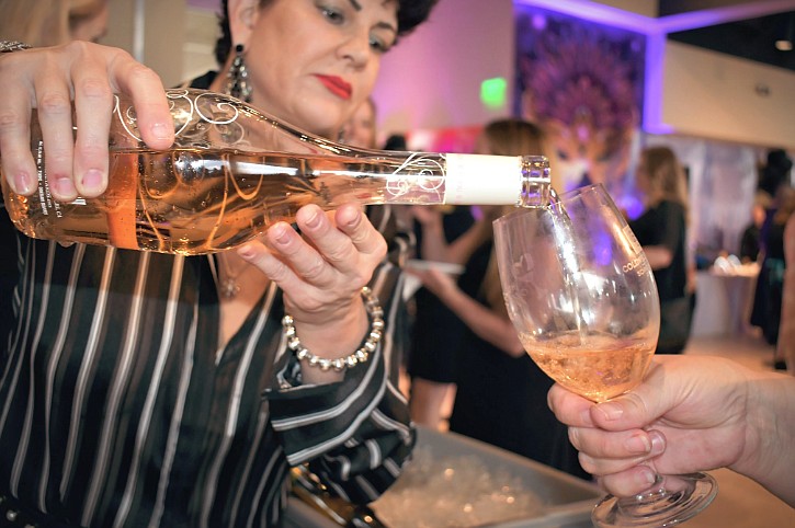 Tiffany Scattaglia, a volunteer with North Idaho Enological Society, pours Daou Rose for a guest at the the Odom Corporation table during the 36th annual Hospice of North Idaho Wine Taste and Auction in the Hagadone Event Center on Saturday. The event brought in $200,000 for the nonprofit.