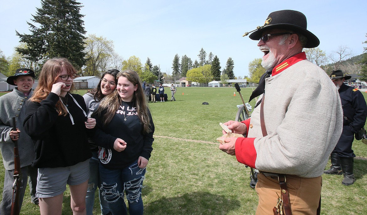 Eighth-grader Alena Wentz tries a piece of hard tack, which is what Civil War soldiers often ate, as Washington Civil War Association Confederate reenactor Ron Clark, who provided the tack, has a laugh on Thursday.