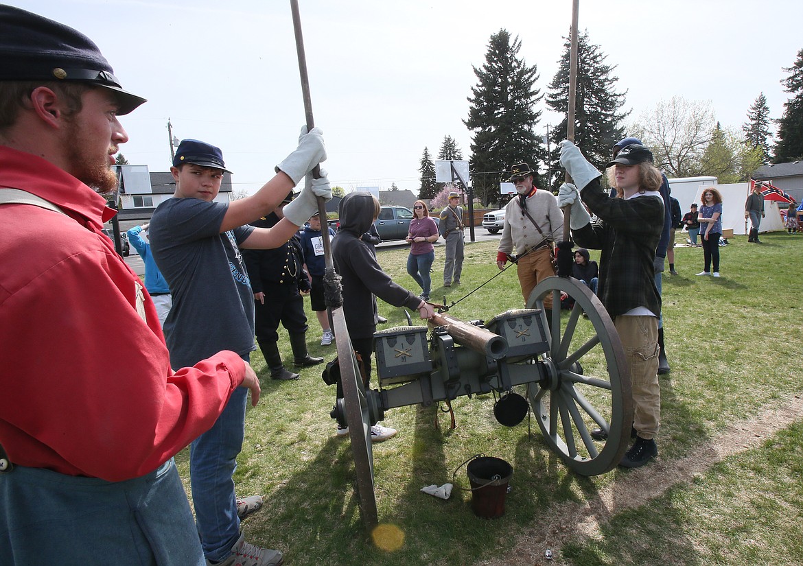 Civil War reenactor Mitchell Black, far left, provides instructions to Logan Trujillo, center left, and Jackson Reasor, right, as they prepare to fire an artillery cannon Thursday at Lakes Middle School.