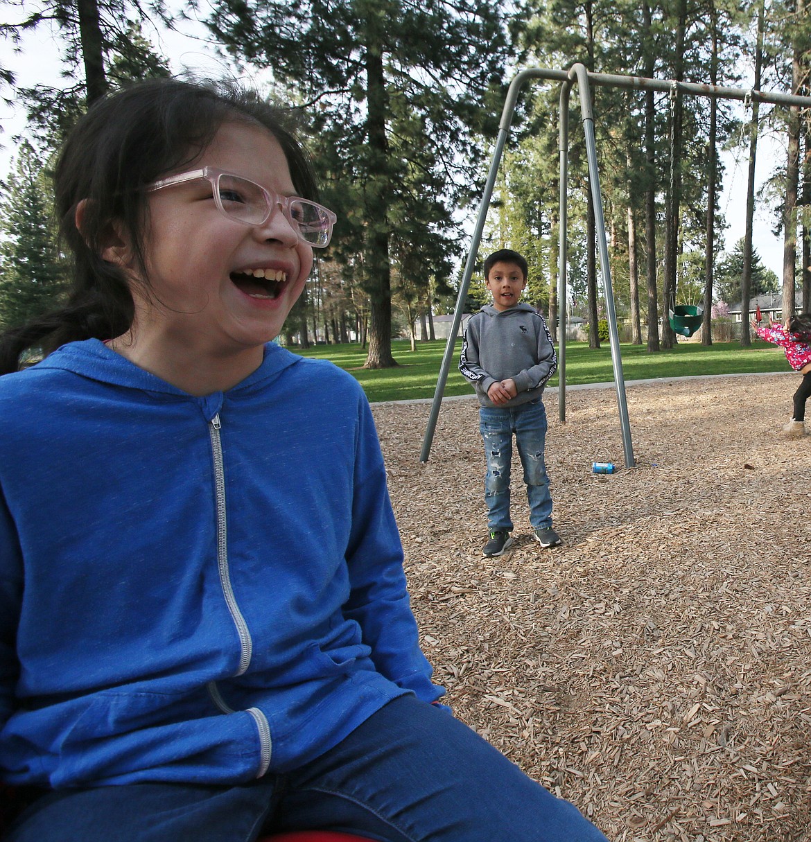 Dakota Walker, left, 10, laughs as she plays in a park in Post Falls on Tuesday. Her adoptive little siblings, Jeremiah, 7, and Aaliyah 3, are in the background.