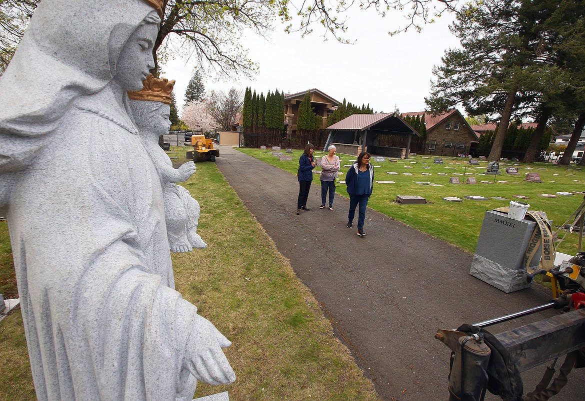 Tina Johnson, Williene Gagnon and Annemarie Lander chat as they watch the new statues being put in place at St. Thomas Cemetery on Friday.