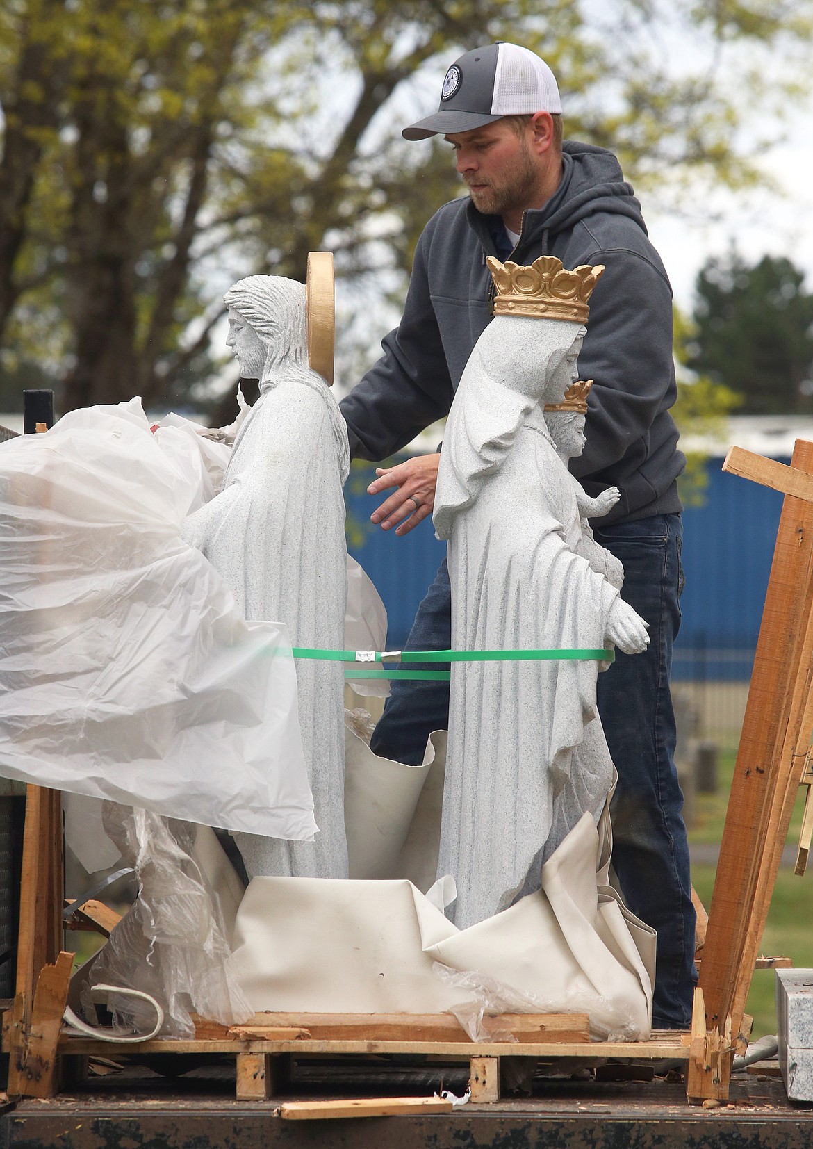 TJ Harris unwraps the new statues for St. Thomas Cemetery on Friday.