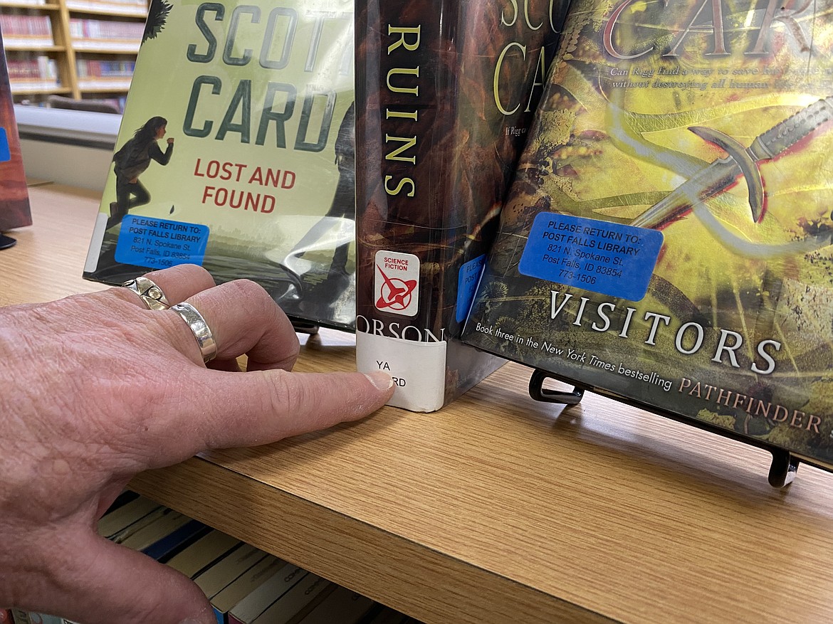 Materials within the Community Library Network are clearly marked, Director John Hartung said, to alert readers of recommended age levels and genres. In this photo, Hartung points to a 'YA' label, meaning young adult. (MADISON HARDY/Press)