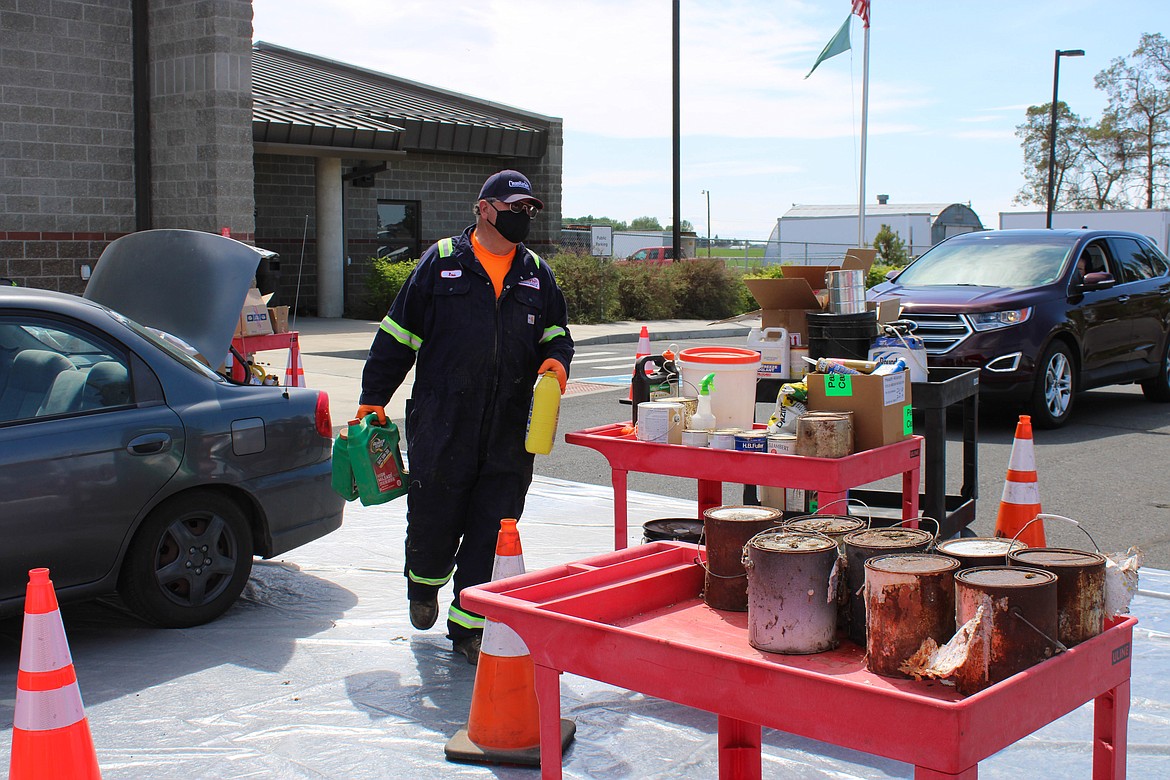 Public Works staff Matthew Monroe collect material from cars at the Household Hazardous Waste event on Saturday.