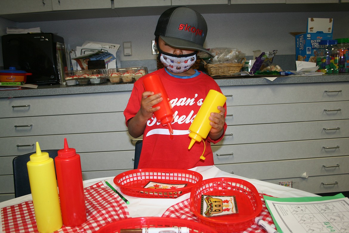 Dean Wilson practices sounding out words with the help of ketchup and mustard bottles. Peninsula Elementary kindergarten teacher Heidi Ragan focused all class activities around baseball on Opening Day Friday.